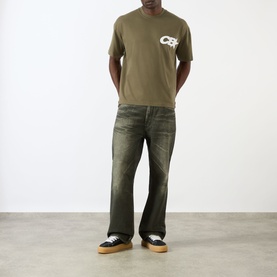 Model wearing Cole Buxton khaki cotton T-shirt, styled with dark distressed jeans and black and white trainers.