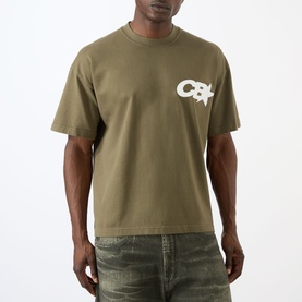 Model wearing Cole Buxton khaki cotton T-shirt with chest logo graphic, styled with distressed green jeans