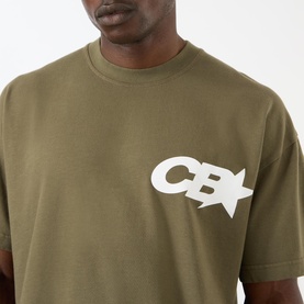 Model wearing Cole Buxton khaki cotton T-shirt, close-up of chest showing CB star logo print.
