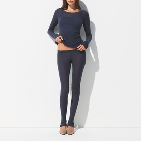 Model wearing Skims Leggings Sleet in dark grey, styled with a matching long-sleeve top and nude heels
