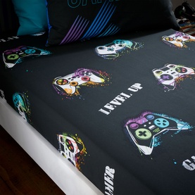 Catherine Lansfield Game Over Fitted Sheet in black with colourful gaming controller print and Level Up slogan, shown on a bed
