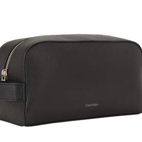 Calvin Klein Foil Logo Wash Bag in black grained leather, silver-tone top zip fastening, side carry handle and embossed logo to front.
