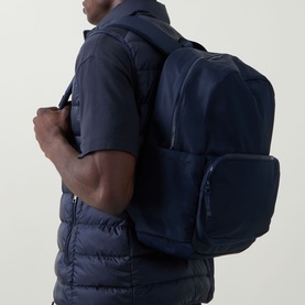 Model carrying Lululemon Everywhere Backpack 22L in True Navy, worn with a navy quilted gilet and short-sleeve top.
