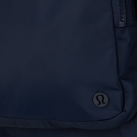 Lululemon True Navy backpack close-up showing tonal zip and embossed logo detail on smooth nylon fabric.