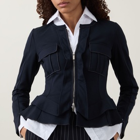 Model wearing HIGH Sapphire Pocket Jacket in navy with two-way zip, chest pockets, peplum hem, styled with white shirt and striped trousers
