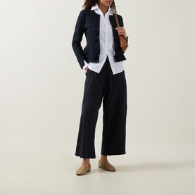 Model wearing HIGH Sapphire Pocket Jacket in navy with white shirt, black pinstripe wide-leg trousers and beige loafers
