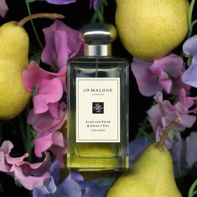 Jo Malone English Pear & Sweet Pea Cologne bottle surrounded by fresh pears and pink sweet pea flowers