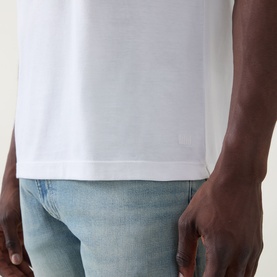 Model wearing Boss Black Casual white crew neck T-shirt in cotton-silk blend, close-up of hem detail, styled with light wash jeans.