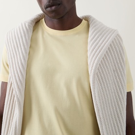 Model wearing Boss Black Casual Taut Logo T-Shirt in Beige Overflow, crew neck, styled with a white ribbed knit open cardigan.