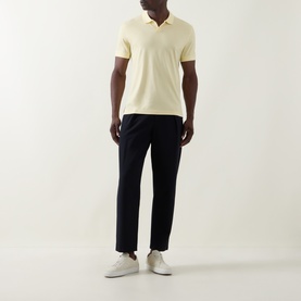 Model wearing Boss Black Casual Ponti 75 Polo Shirt in Beige Overflow with navy trousers and white trainers.