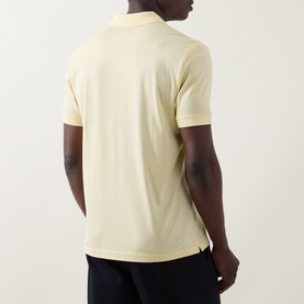 Model wearing Boss Black Casual Ponti 75 Polo Shirt in Beige Overflow, back view, styled with dark navy trousers.