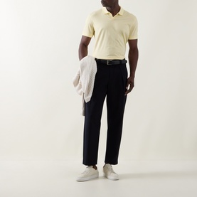 Model wearing Boss Black Casual Ponti 75 Polo Shirt in Beige Overflow, styled with navy trousers, white trainers, and a draped knit cardigan.