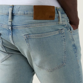 Model wearing Boss Black Casual Classic Fit Straight-Leg Jeans in turquoise/aqua, showing rear with logo patch and authentic light wash fading.