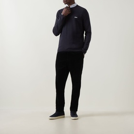 Model wearing Boss Green Label dark blue cotton crew neck jumper with white collar detail, styled with black trousers and navy trainers