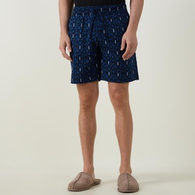 Model wearing Hugo Milo Logo Pyjama Shorts in dark blue with allover logo print and elasticated waistband, styled with beige slippers