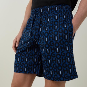 Model wearing Hugo Milo Logo Pyjama Shorts in dark blue all-over logo print, elasticated waistband with drawstring, paired with black T-shirt