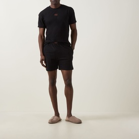 Model wearing Hugo Galaxy Shorts Pyjama Set in black, two-piece crew neck tee and shorts with logo badge, styled with nude slippers