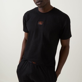Model wearing Hugo Galaxy Shorts Pyjama Set in black, showing crew neck short-sleeve top with logo badge, styled with matching black shorts.