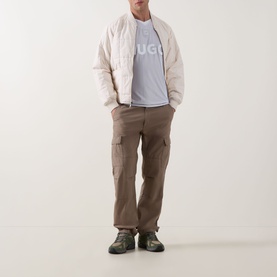 Model wearing Hugo Dwild Logo T-Shirt in light/pastel green, styled with cream padded jacket, brown cargo trousers and green hiking boots.