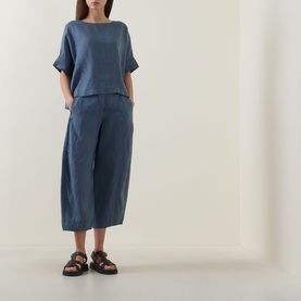 Model wearing Oska Lightweight Solid T-Shirt in blue linen with matching blue cropped wide-leg trousers and black sandals.