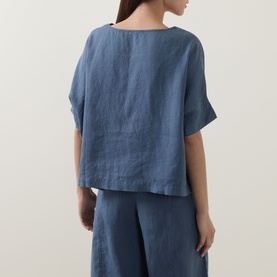 Model wearing Oska Lightweight Solid T-Shirt in blue linen, back view, styled with matching blue wide-leg trousers