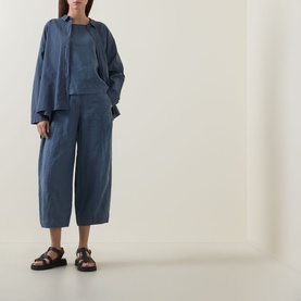 Model wearing Oska Lightweight Solid T-Shirt in blue, styled with matching blue wide-leg trousers, overshirt, and dark brown sandals.