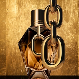 RABANNE Million Gold For Her Parfum 50ml, angular dark bottle with gold chain link detail against gold textured background