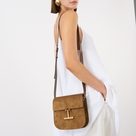 Model carrying Tom Ford Suede Leather Mini Crossbody Bag in Whisky with gold-tone T-logo hardware and adjustable strap, styled with white dress