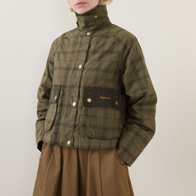 Model wearing Barbour Beadnell Tartan Cropped Jacket in green tartan with corduroy pocket flaps and gold snap buttons, styled with brown wide-leg