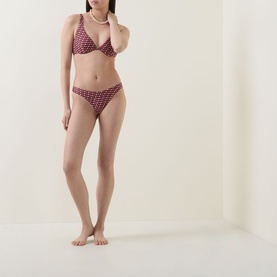 Model wearing Jets rose geometric print bikini brief with matching triangle top, styled with pearl necklace