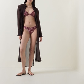Model wearing Jets Rose geometric print bikini top and matching briefs, styled with dark sheer cover-up and flip flops