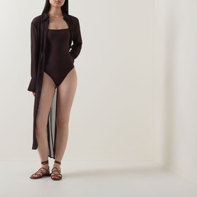 Model wearing Jets Alessia Textured Swimsuit in Chocolate with a sheer dark cover-up and lace-up flat sandals.