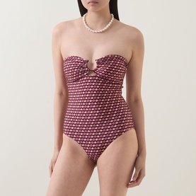 Model wearing Jets rose geometric print strapless swimsuit with ring detail, styled with pearl necklace