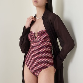 Model wearing Jets rose floral-print swimsuit with sweetheart neckline, styled with sheer black cover-up and pearl necklace.