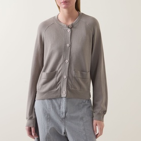 Model wearing Transit Patch Pocket Cardigan in Rope, round neck, button front, patch pockets, styled with grey striped trousers.