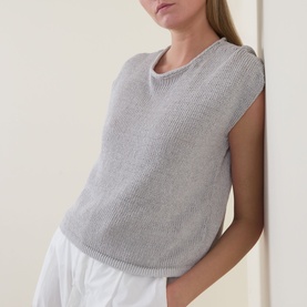 Model wearing Transit Open-Knit Sweater in light grey, round neck, cap sleeves, ribbed trim, styled with white wide-leg trousers