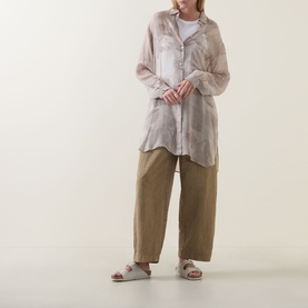 Model wearing Transit Tonal Printed Longline Shirt in sand, semi-sheer with high-low hem, styled with khaki wide-leg trousers and slide sandals.