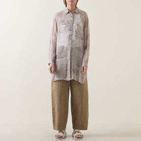 Model wearing Transit Tonal Printed Longline Shirt in sand, semi-sheer with high-low hem, styled with wide-leg khaki trousers and sandals.