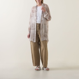 Model wearing Transit Tonal Printed Longline Shirt in Sand, semi-sheer with high-low hem, styled with khaki wide-leg trousers and sandals.