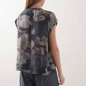 Model wearing Transit Abstract Print Blouse in Blu Slate, back view, cap sleeves, curved hem; styled with grey wide-leg trousers.