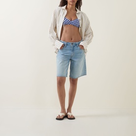 Model wearing Seafolly Marseille Bralette Bikini Top in Blue Indigo checkerboard print, styled with light wash denim shorts and brown sandals.