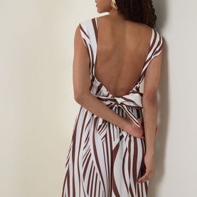 Model wearing Seafolly Striped Tiered Dress in Cocoa, showing low-cut open back with knotted strap detail and adjustable tie fastening.