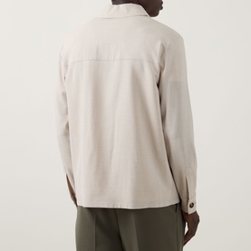 Model wearing Slowear Silk Flap Pocket Overshirt in stone, rear view, with olive trousers. Long sleeves with buttoned cuffs visible.