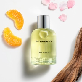 Burberry Weekend For Women Eau de Parfum bottle with citrus slices, rose petals and wood bark on white background