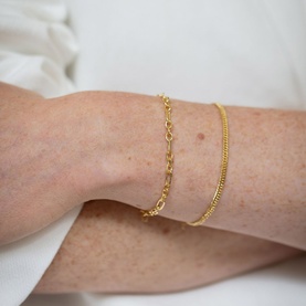 Model with Juvi Figaro Chain Bracelet in gold vermeil, featuring alternating open links, styled with a curb chain bracelet on wrist