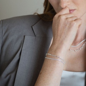 Model with Juvi Figaro Chain Bracelet in silver sterling silver, alternating open links, styled with matching chain necklace and grey blazer