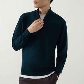 Model wearing John Smedley Tapton Extra Fine Knit Half-Zip Sweater in Richardson green, styled over a white crew-neck tee with dark trousers.