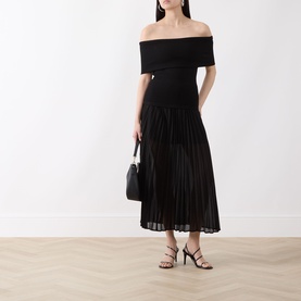Model wearing Selected Femme Millie Pliss&eacute; Pleated Skirt in black, midi length, styled with black off-shoulder top and strappy heels, carrying small