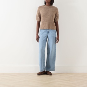 Model wearing Marc O Polo Solid Knit Top in taupe, crew neck, short sleeves, styled with light blue wide-leg jeans and brown loafers.