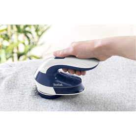 Tefal Fabric Shaver in blue and white, handheld in use on grey fabric, compact circular design with branded logo visible